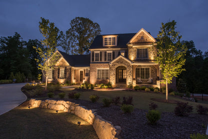 antique brass outdoor wall washer flood light with ground stake installed in landscape shining on wall in front of beautiful home with professional lighting and landscape